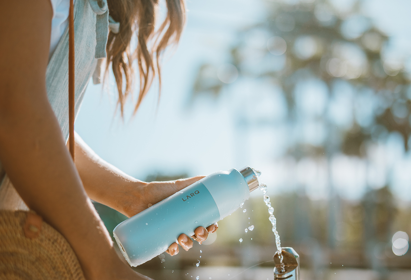 woman filling up seaside mint color LARQ Bottle at a public water fountain