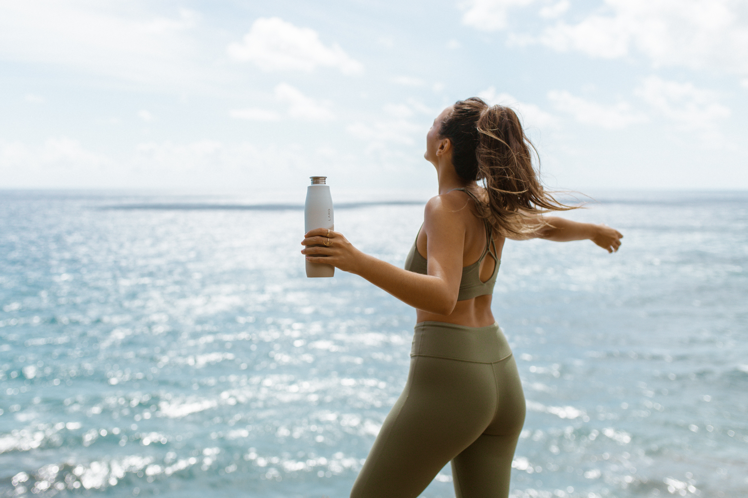 Woman holding LARQ Bottle Movement near ocean